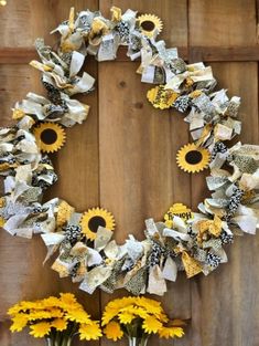 two vases with sunflowers in front of a wooden wall and a wreath made out of newspaper strips