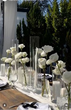 there are many vases with flowers in them on the dining table set for dinner