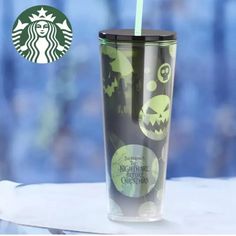 a starbucks cup with a green straw in it and an image of a jack - o'- lantern on the side