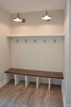 an empty room with two benches and three lights on the wall above them, along with white painted wood flooring