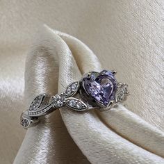 Brilliant sparkle with a captivating Lavender Cubic Zirconia heart shaped stone, this White Gold promise ring has a core of solid 925 Sterling Silver, making it hypoallergenic and built to last! The high-quality faceted lavender heart stone is 6mm (0.8 carat) and has a Mohs hardness of 8-1/2. Sprinkled generously with cubic zirconia rhinestones, this enchanting ring is accented by a nature-inspired tree branch and leaf design. It would make a great promise ring or engagement ring, as well as an Purple Engagement Rings, Lavender Jewellery, Heart Shaped Engagement Rings, White Gold Promise Ring, Heart Shaped Ring, Gold Promise Ring, Heart Promise Rings, Rings Promise, Lavender Heart