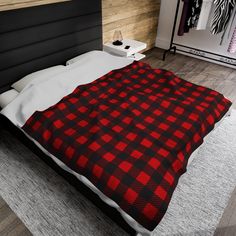 a bed with a red and black checkered blanket on it's headboard