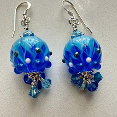 These beautiful shades of blue petal lampwork beads were made by artist, Claire Louise Patrick. I accented them with Swarovski 4 mm carribean blue, light sapphire bicones, Prestige 4 mm aquamarine bicones and rondelles, sterling bead caps and spacers. They will be secure on your ears with sterling shepherd hook ear wires and measure approximately 1 5/8 inches.  Please watch the video for a better representation of the colors. These are the exact earrings you will be receiving, already made and r Carribean Blue, Petal Earrings, Ocean Sky, Light Sapphire, Sky Nature, Organza Gift Bags, Bead Caps, Beaded Dangles, Schmuck Design