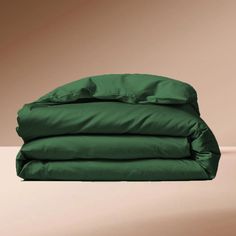 the green sheets are stacked on top of each other in front of a brown wall