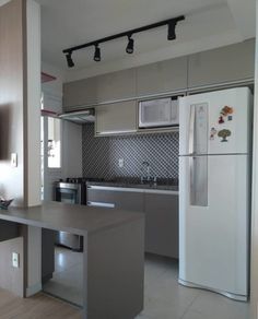 an empty kitchen with stainless steel appliances and counter tops in front of a tv mounted on the wall