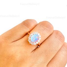 a woman's hand holding an opal and diamond ring