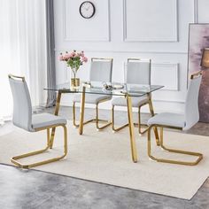 a glass dining table with gold legs and white chairs