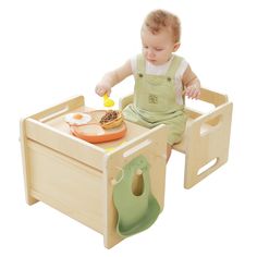 a baby sitting in a wooden chair with food on it's tray and eating utensils