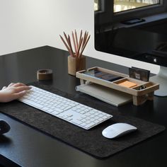 a person sitting at a desk using a computer keyboard and mouse pad to work on their computer