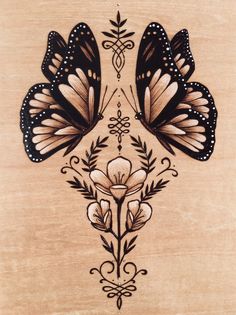 two butterflies are sitting on top of a piece of wood that is decorated with flowers and leaves