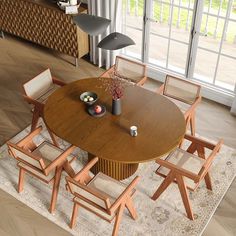 a dining room table with chairs and a vase on it in front of a large window