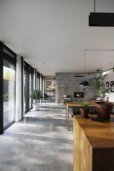 a long hallway with potted plants on the side and large glass doors leading to another room