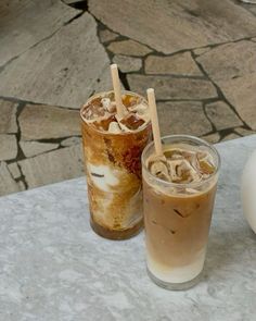 two iced drinks sitting on top of a table next to an egg shell shaped object