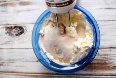 an electric mixer mixing cream in a blue bowl