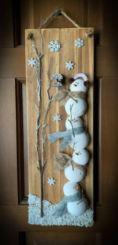 a wooden sign with snowmen and branches on it