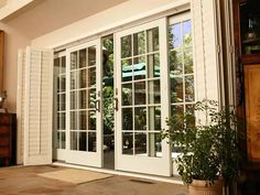 an open window with white shutters and potted plant