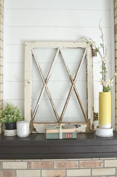 a fireplace mantel with books, plants and vases sitting on top of it