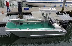 a small boat docked at a dock with a man in the distance walking by it