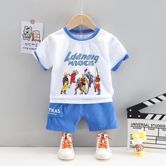 Toddler Boy Superman Pattern Shirt T-shirt & Shorts Wholesale Children's Clothing - PrettyKid Blue Short Sleeve Sets With Letter Print, Light Blue Cotton Short Sleeve Sets, Cotton Character Print Sets For Playwear, White Character Print Summer Sets, White Character Print Sets For Summer, Blue Cotton Character Print Sets, Blue Cotton Sets With Character Print, Blue Cotton Set With Graphic Print, Blue Cotton Sets With Graphic Print