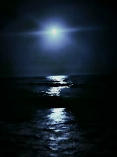 the moon is shining over the ocean at night