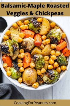 a bowl filled with vegetables and chickpeas on top of a white table next to a spoon