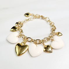 Vintage hearts are the focal point of this love filled bracelet. An assortment of gold plated hearts and matte ivory hearts play along the edge, perfect as a gift for someone you love. Handmade in the United States, a matching necklace and earring set are available. Features: - Gold Plated Vintage Hearts - Matte Ivory Vintage Hearts - Gold Plated Mixed Cable Chain - Lobster Claw Clasp - Extension - Handmade in the United States Dimensions: - Length: 7.5" - Extension: 1" - Total Length: 8.5" Dainty White Heart Bracelet For Anniversary, White Heart Charm Bracelet For Anniversary, Gold Metal Charm Bracelet With Heart Beads, Elegant White Heart Bracelet For Valentine's Day, White Heart-shaped Metal Charm Bracelet, Elegant White Heart Charm Bracelet, Elegant White Charm Bracelet With Heart Charm, White Bracelets With Heart Charm For Anniversary, White Heart Beads Bracelet For Weddings