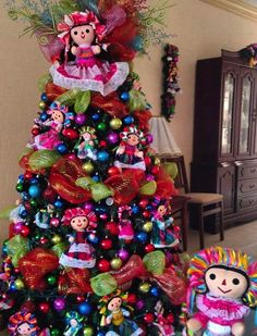 a christmas tree decorated with colorful ornaments and decorations is shown next to a small doll