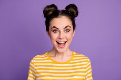 a woman with two hair buns on her head and wearing a yellow striped shirt