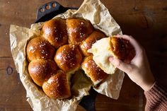 a person holding a piece of bread in front of it on top of wax paper