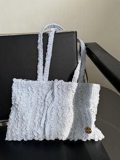 two purses sitting on top of a black table next to each other and one is white