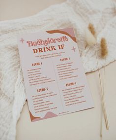 a pink drink list sitting on top of a table next to a knitted blanket