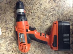 an orange and black cordless drill is on the counter