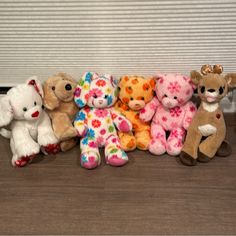 a group of stuffed animals sitting next to each other on a wooden floor in front of a window