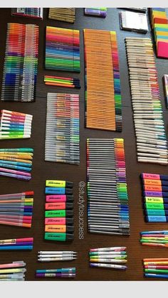 many different colored pencils are laid out on a table with markers and pens in them