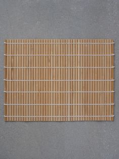 a close up of a bamboo mat on a gray surface with white pins sticking out of it