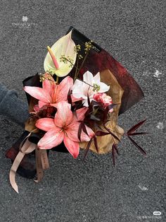 a bouquet of flowers sitting on the ground next to someone's leg and shoes