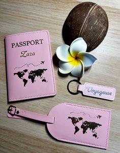 two pink luggage tags and a flower on a wooden table with a white franette