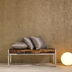 a couch with pillows on it next to a lamp in front of a concrete wall