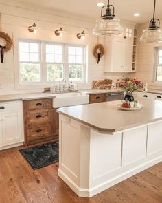 a large kitchen with white cabinets and wood flooring on the walls, along with an island in the middle