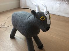 a stuffed animal that looks like a bull with horns on it's head is sitting on the floor