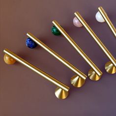 six brass door handles and knobs on a purple surface with marble balls in the background