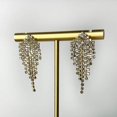 Welcoming back the glitzy tassel earring trend with open arms! The shiny crystal gemstone tassels on this glamorous statement earring sparkle from a mile away. Length: 45mm Product Materials/Dimensions: 20mm wide x 45mm long. 16k electric gold plating over brass. Clear glass stones. Tassel Earring, Earring Trends, Statement Earring, Open Arms, Sparkle Earrings, Tassel Earrings, Crystals And Gemstones, Gold Plating, Statement Earrings