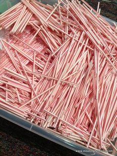 a container filled with lots of candy canes on top of a carpeted floor