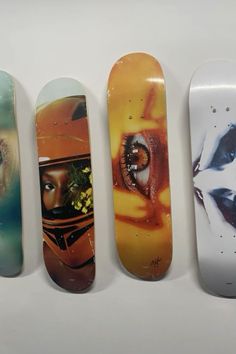 four skateboards with different designs on them are lined up against a white background and one has an image of a woman's face