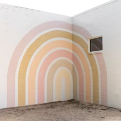 an empty room with a rainbow painted on the wall and a window in the corner