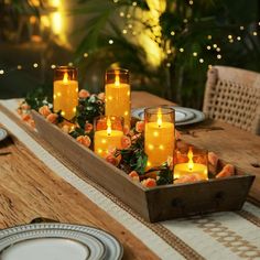 a wooden tray with candles on top of it sitting on a table next to plates and utensils