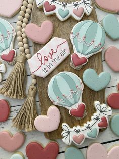 decorated cookies are arranged on a wooden board with the words love is in the air