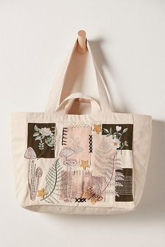 a tote bag hanging on a wall with flowers and plants in it, along with a wooden hanger