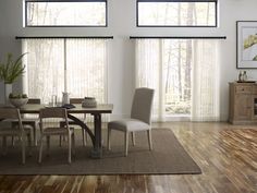 a dining room table and chairs in front of two large windows with blinds on them