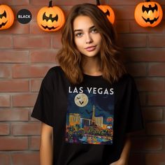 Celebrate Halloween with this Las Vegas Halloween theme T-Shirt.  Makes a great gift. This classic unisex jersey short sleeve tee fits like a well-loved favorite. Soft cotton and quality print make users fall in love with it over and over again. These t-shirts have-ribbed knit collars to bolster shaping. The shoulders are tapered for a better fit over time. Dual side seams hold the garment's shape for longer. .: Made with 100% Airlume combed and ring-spun cotton, a lightweight fabric (4.2 oz/yd² Halloween Black T-shirt With Character Print, Halloween Band Merch T-shirt With Funny Print, Halloween Novelty T-shirt For Streetwear, Novelty Halloween T-shirt For Streetwear, Halloween Streetwear Shirt With Sublimation Print, Black Novelty T-shirt With Custom Print, Halloween Band Merch Shirt, Band Merch Halloween Fan Shirt, Halloween Band Merch Shirt With Crew Neck